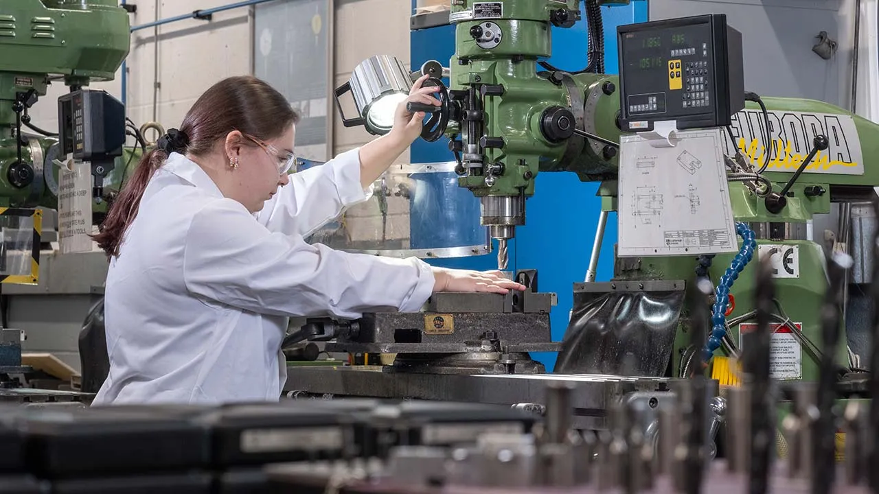 A student in a lab coat is operating large machinery