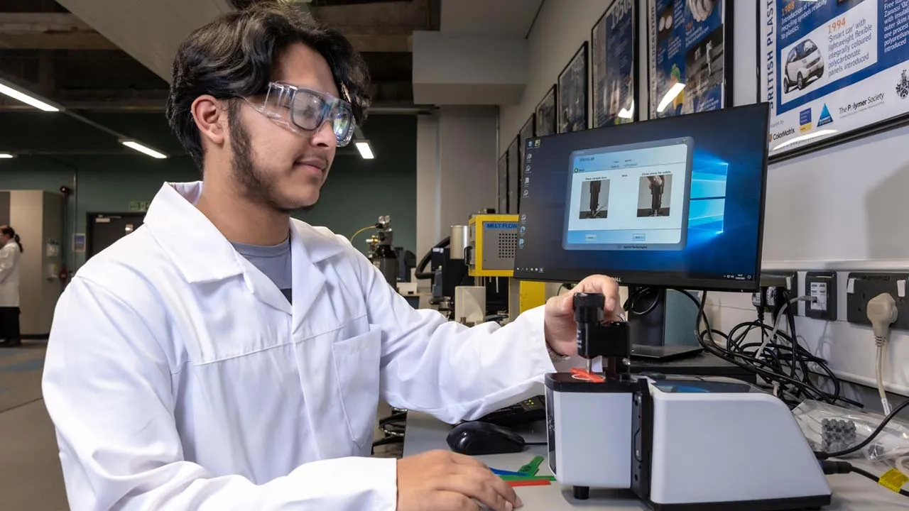 A man in a lab coat focused on his computer and analysing data in a laboratory setting
