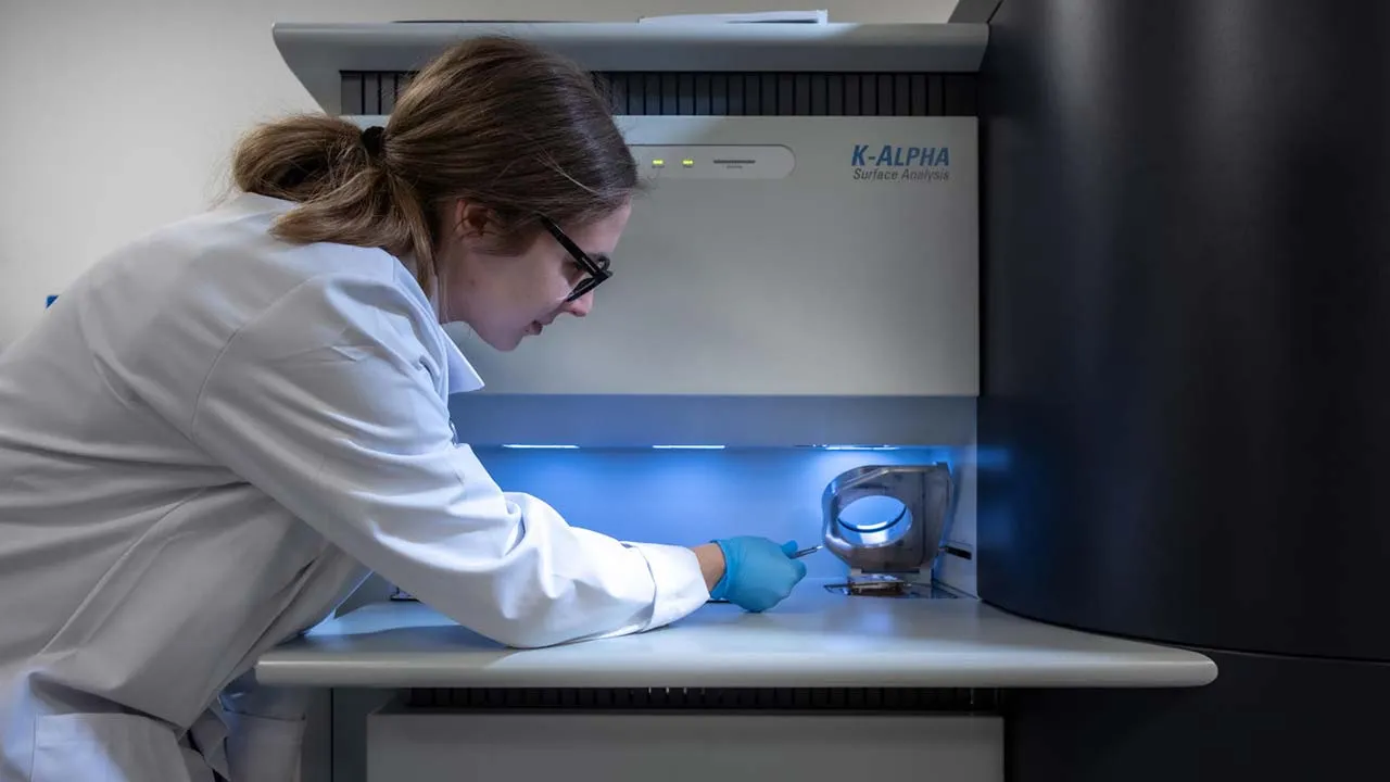 A student wearing a lab coat is conducting an experiment in a laboratory