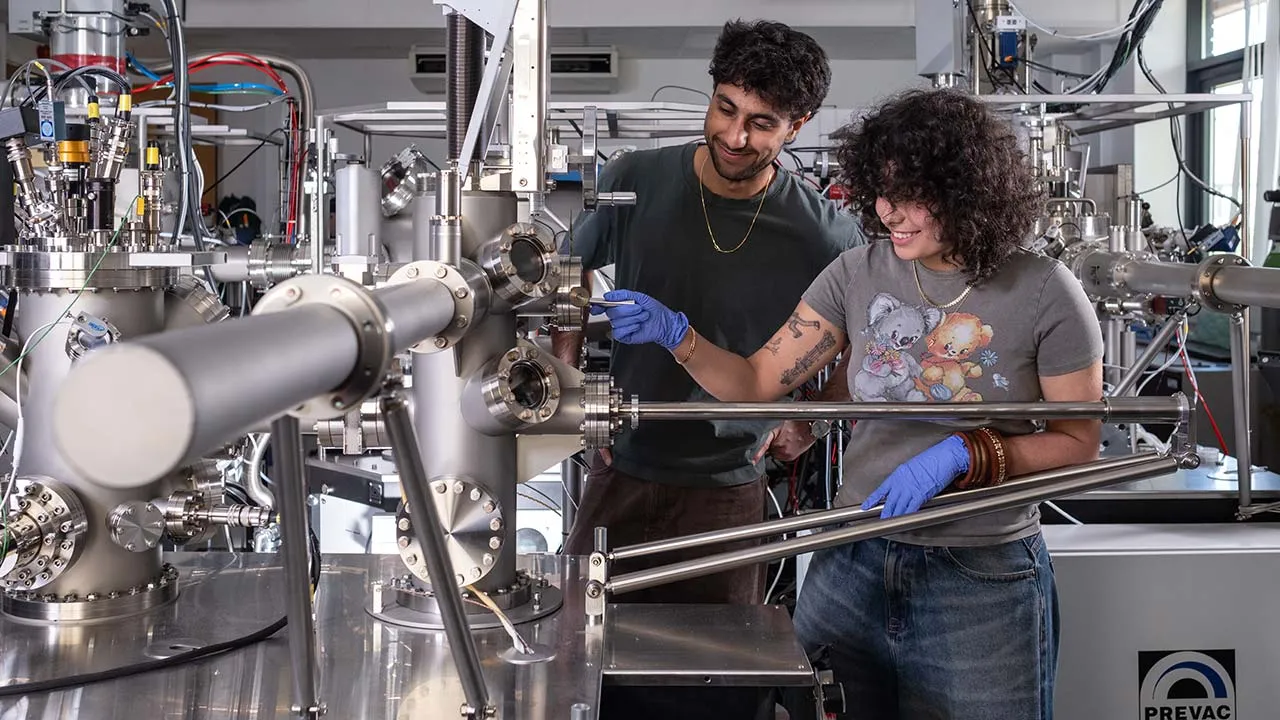 Two students working together at a machine, immersed in their scientific research and experiments