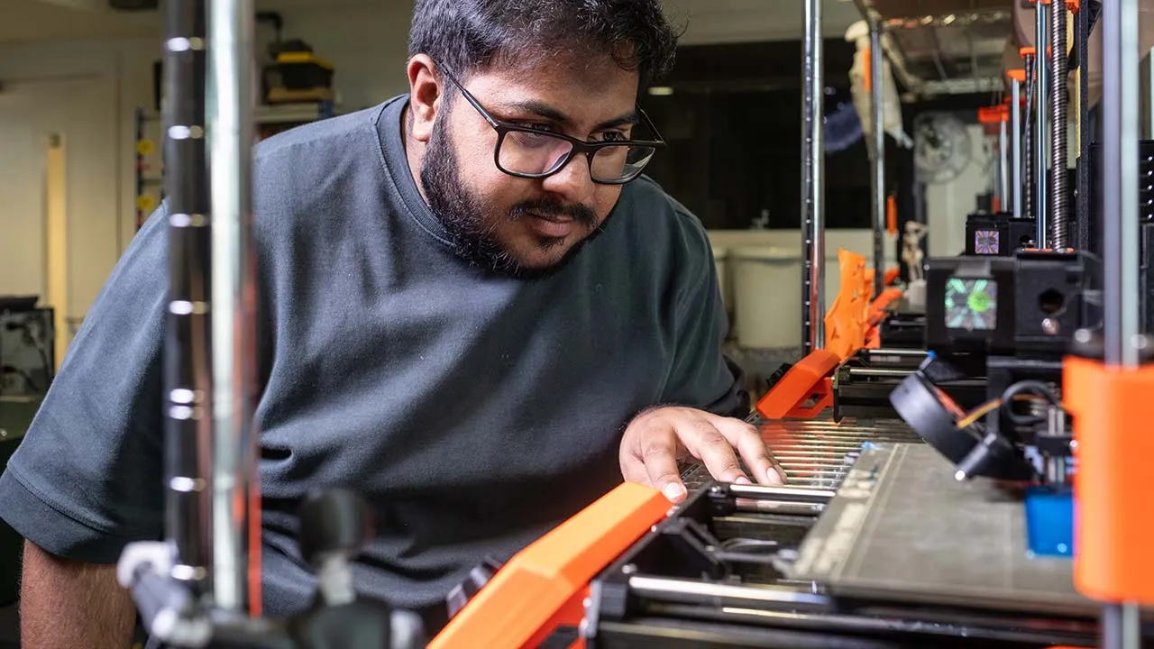 A student is looking closely at some machinery in a lab