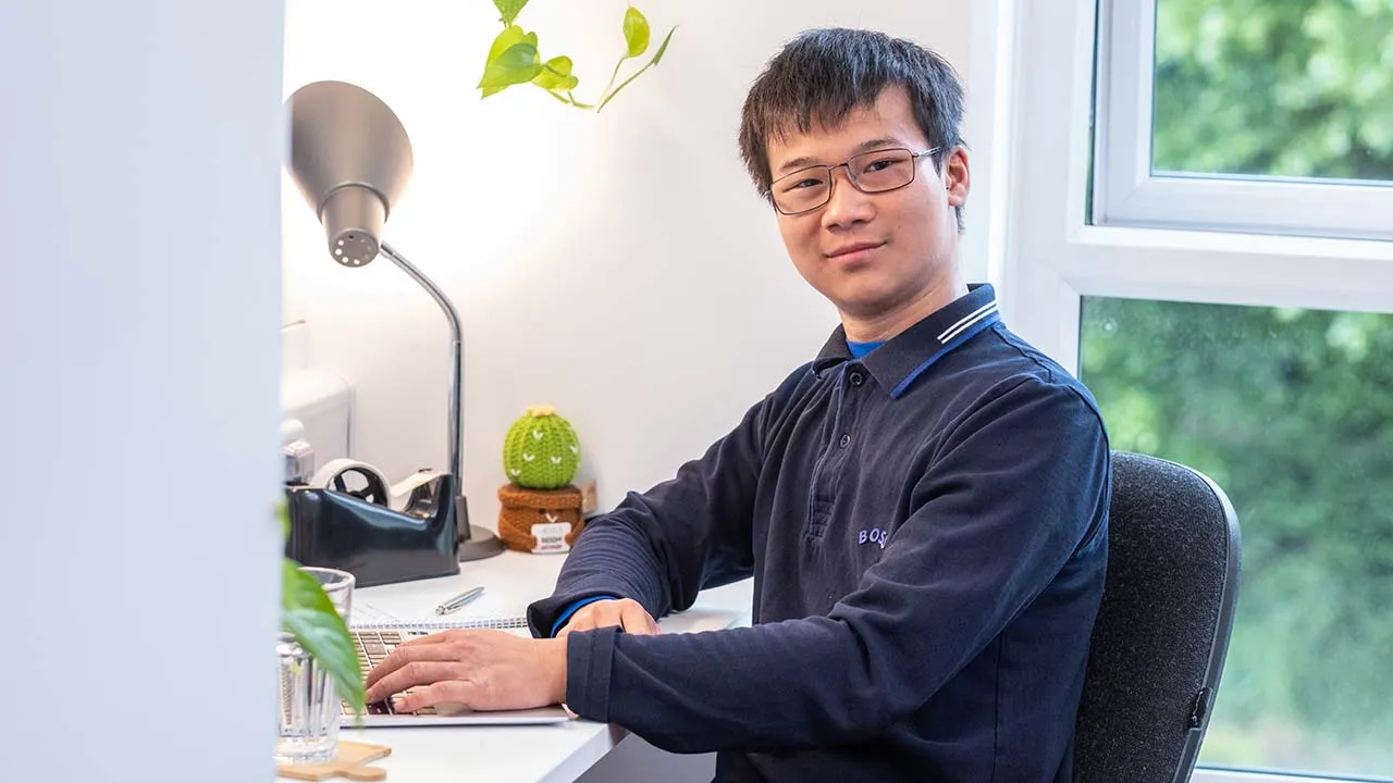 A student sat working at a desk in their student accommodation