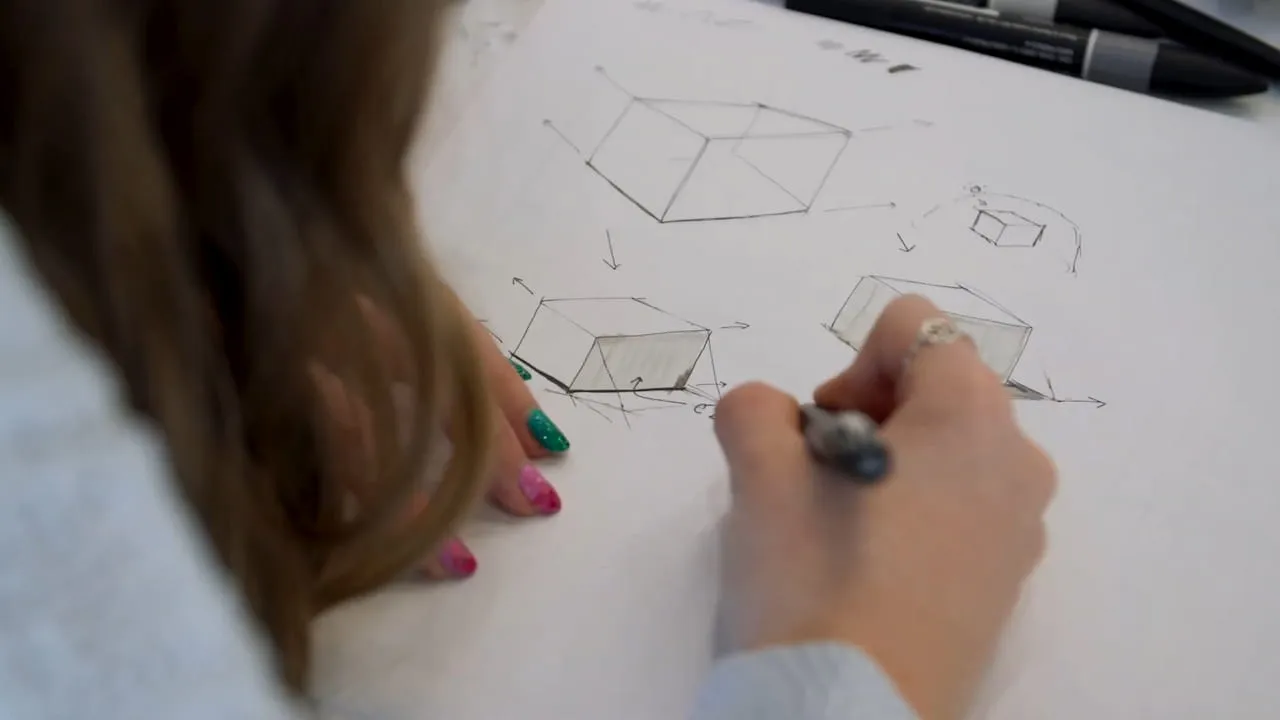 A student sketching 3D shapes on a drawing pad