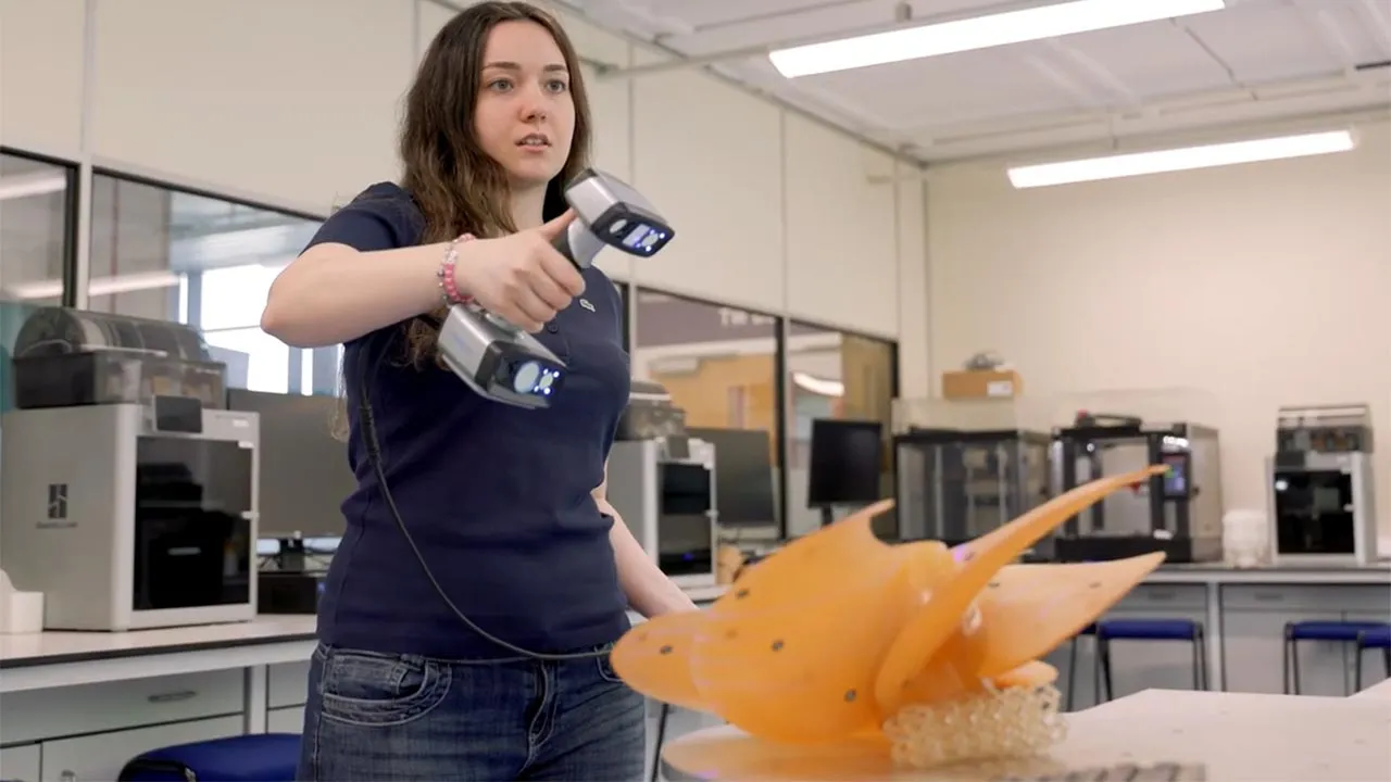 A student holding a camera device and carrying out research in a lab