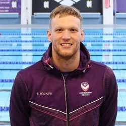 Felix Aubock wearing a purple Loughborough Sport top stood by a swimming pool.