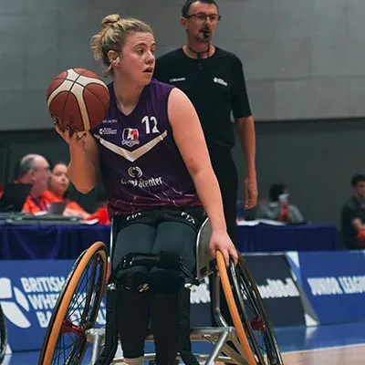 Lucy Robinson on the wheelchair basketball court holding the ball