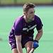 Jonty Griffiths on a green hockey pitch holding a hockey stick