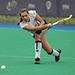 Giselle Ansley on a green hockey pitch holding a hockey stick