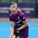 Izzy Petter on a blue hockey pitch holding a hockey stick