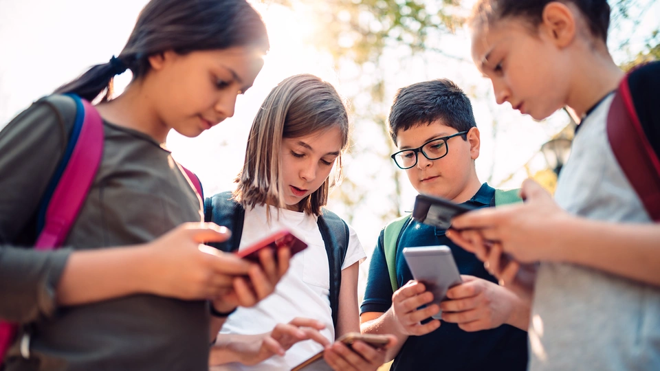 A group of four children looking at mobile phone devices