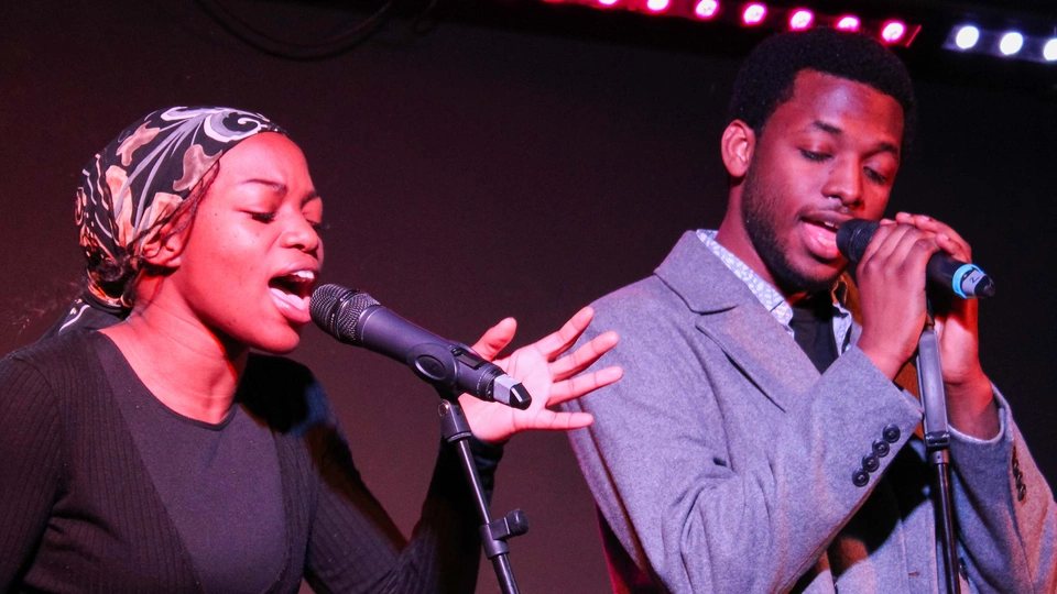 Two singers standing at microphones singing