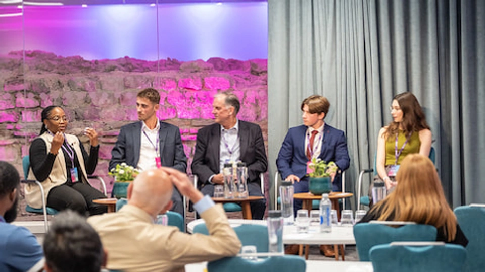 Five people seated on a stage facing an audience