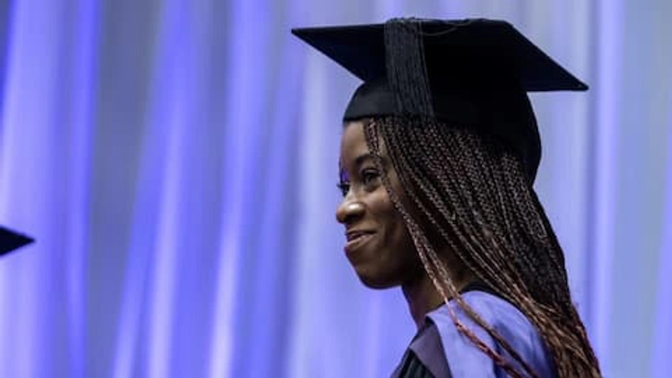 A graduate smiling wearing a cap and gown
