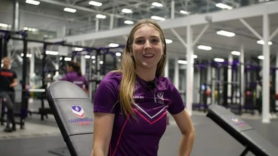 Student Jess in a Loughborough Sport top, smiling in the gym