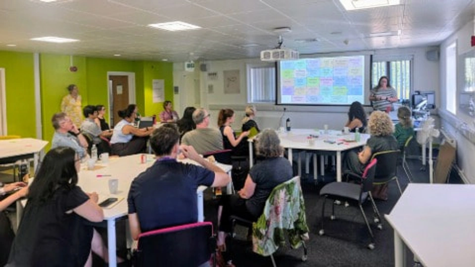 Group of people in clasroom looking at a diagram on projected screen