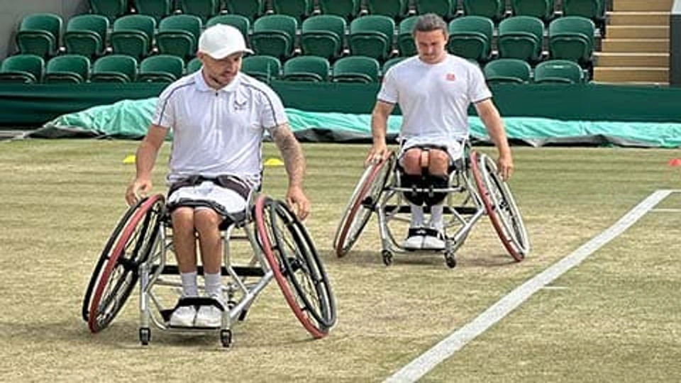 Two wheelchair tennis players on a grass court