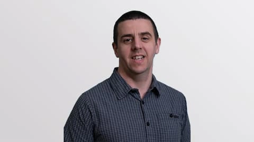 Keith Yendall wearing a checked shirt standing in front of a white background
