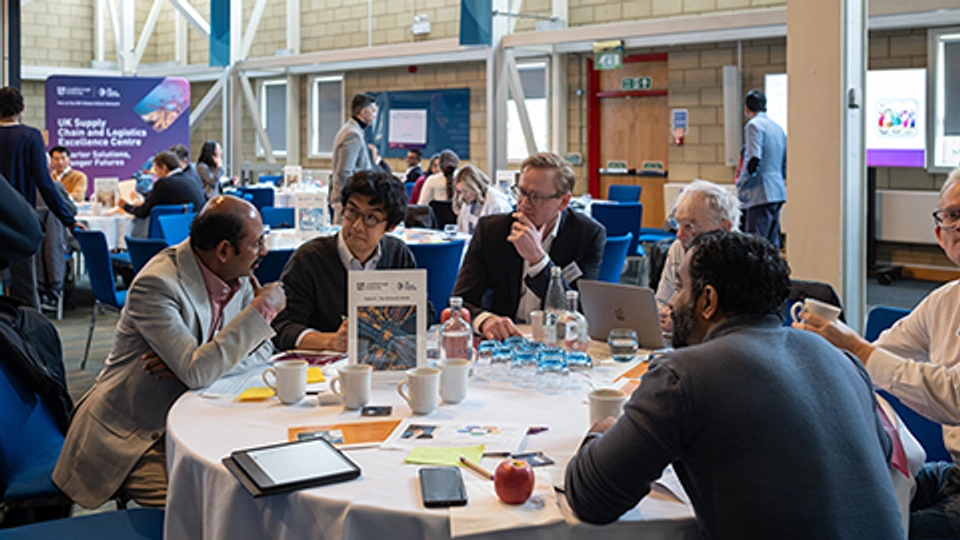 Academics in discussion around tables during a UK supply chain network workshop.
