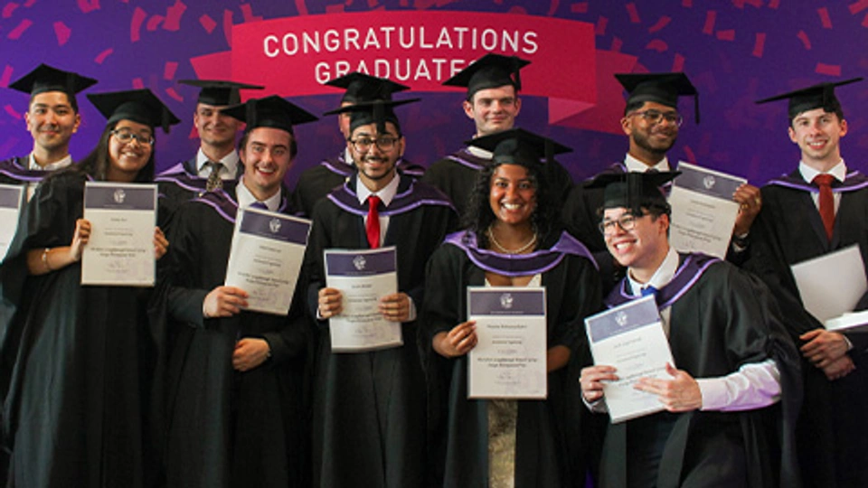 Graduates in cap and gown holding certificates