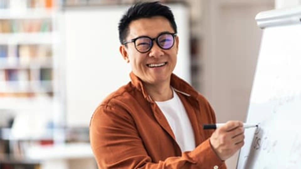 A japanese man writing on a whiteboard
