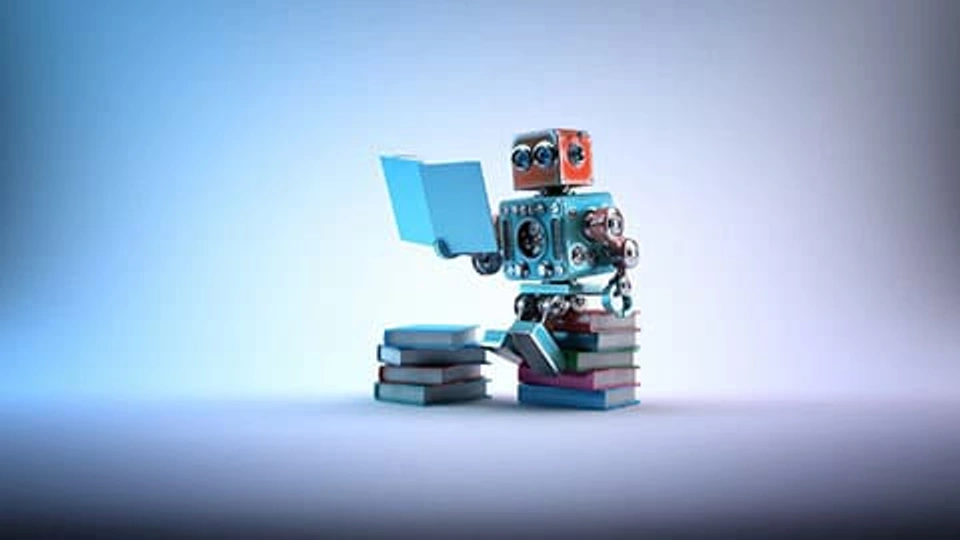 Animated image of a robot sat on a pile of books reading a book