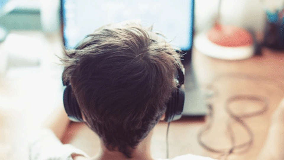 a boy wearing headphones looking at a laptop