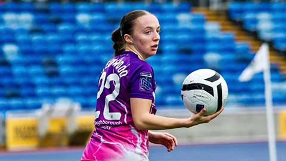 Player Doris Greenwood holding a football with her back turned to the camera