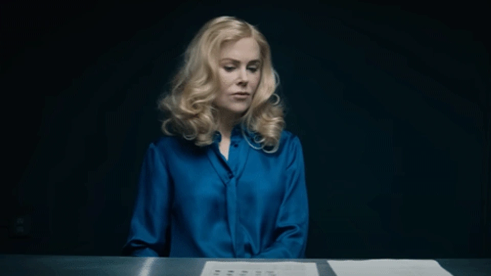 Nicole kidman sat at a desk in a dark room