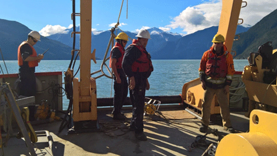 People working on a boat with mountains in the distance