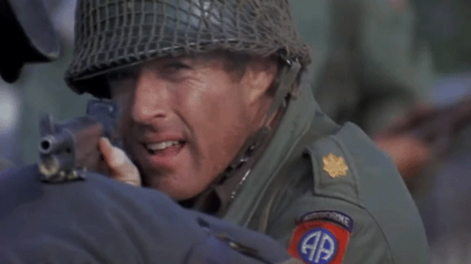 A man in miltary uniform pointing a gun