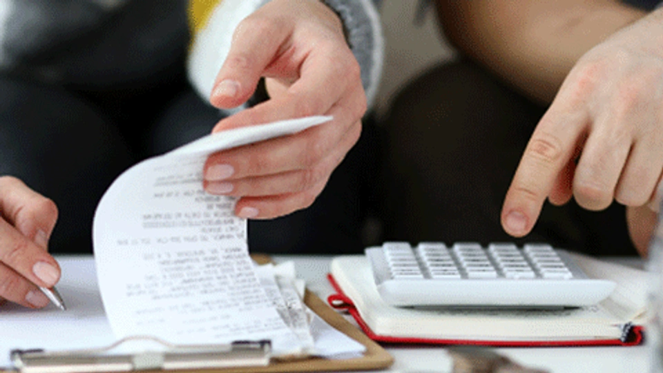 hands of two people using a calculator and looking at a receipt