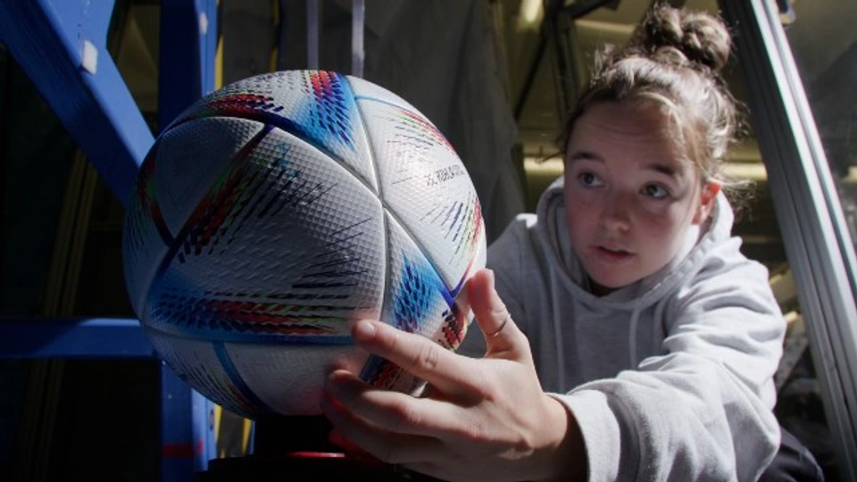 Close-up of a student placing a football into a piece of testing equipment. 