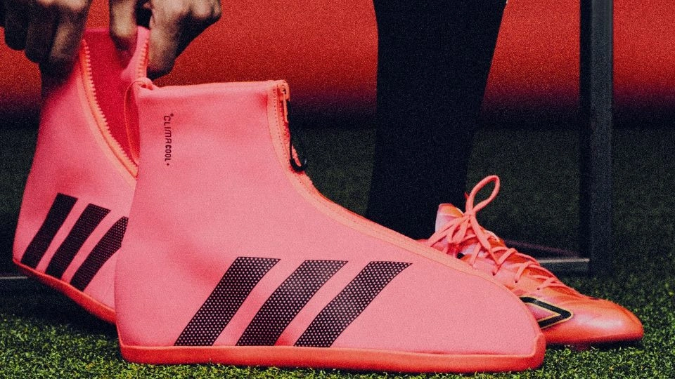 Someone is about to put on adidas’ CLIMACOOL SYSTEM overshoe. This is a pink textile boot with three black stripes on the side