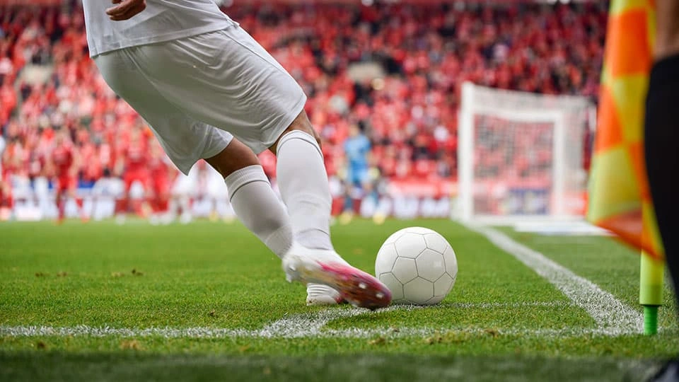A football player taking a corner on the pitch with the bottom half of the body visible