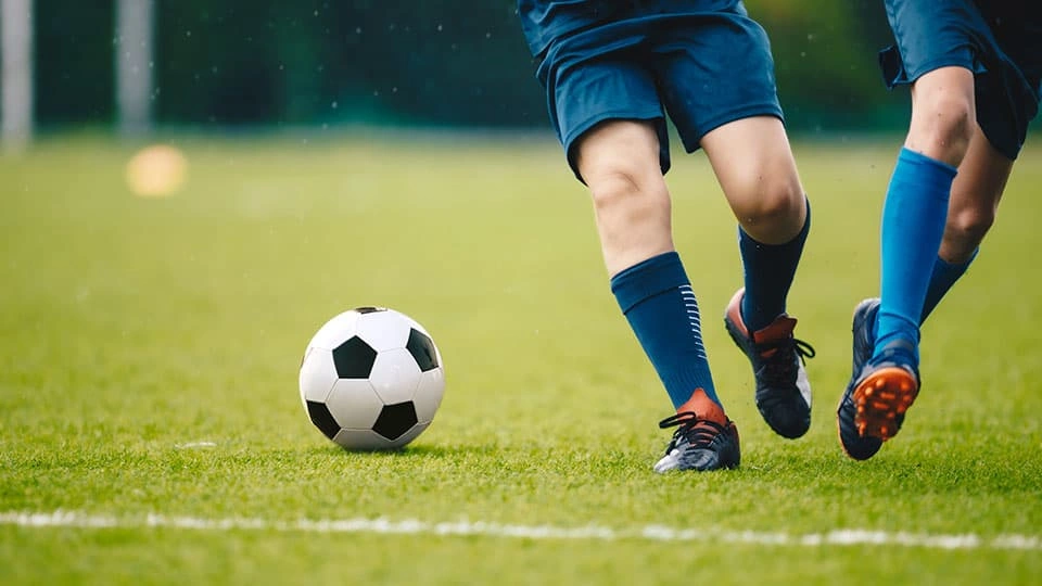 A football on a field with two players running after it