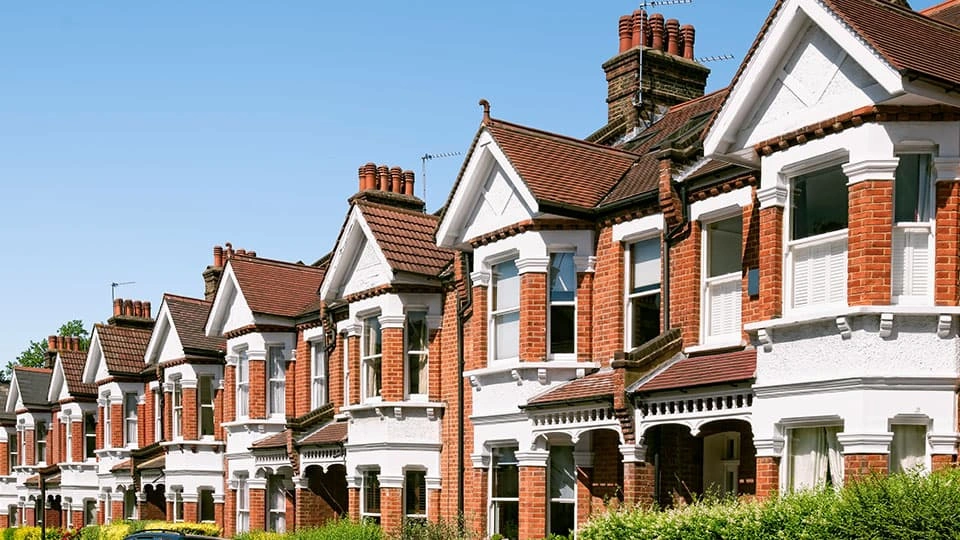 A row of houses with orange brown bricks facing the sun with blue sky