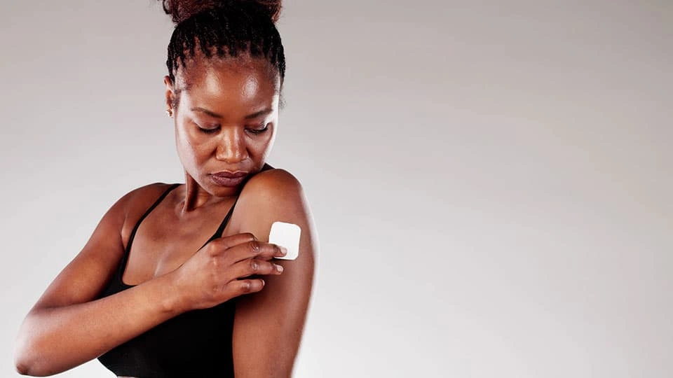 A woman putting a white square patch on her arm