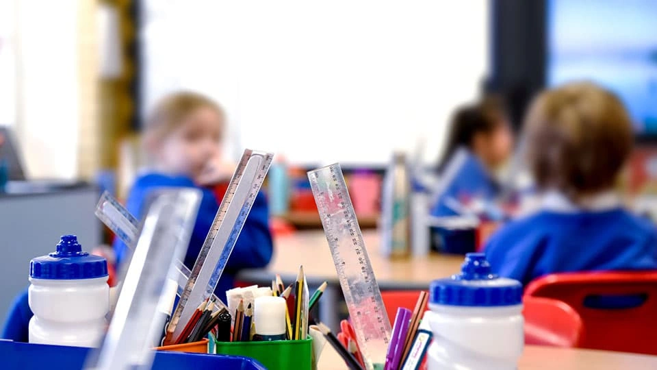School children in a classroom with the focus on classroom tools in a pencil pot