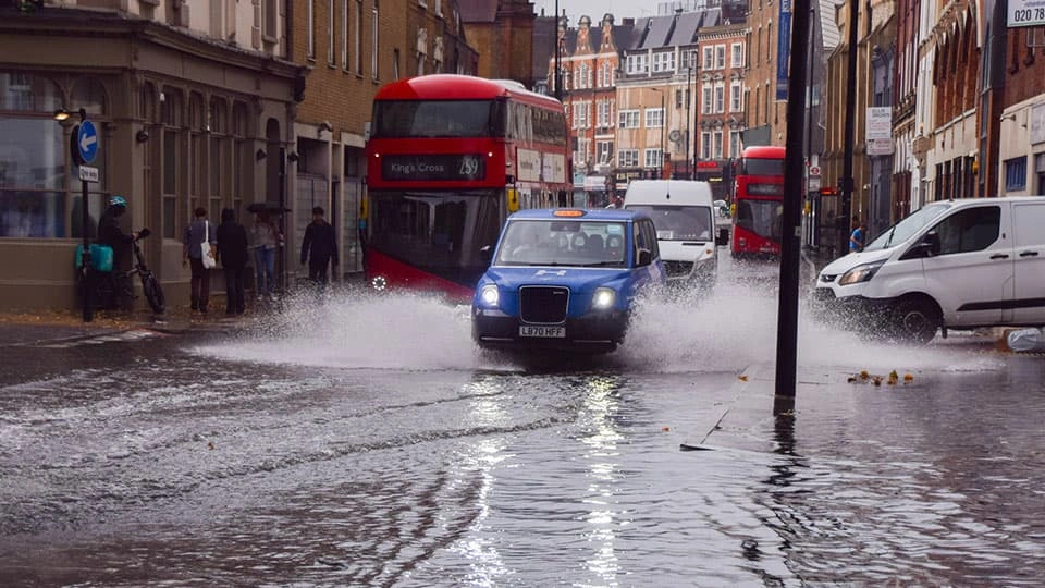 Buses, taxis, and vans driving through flood water in London