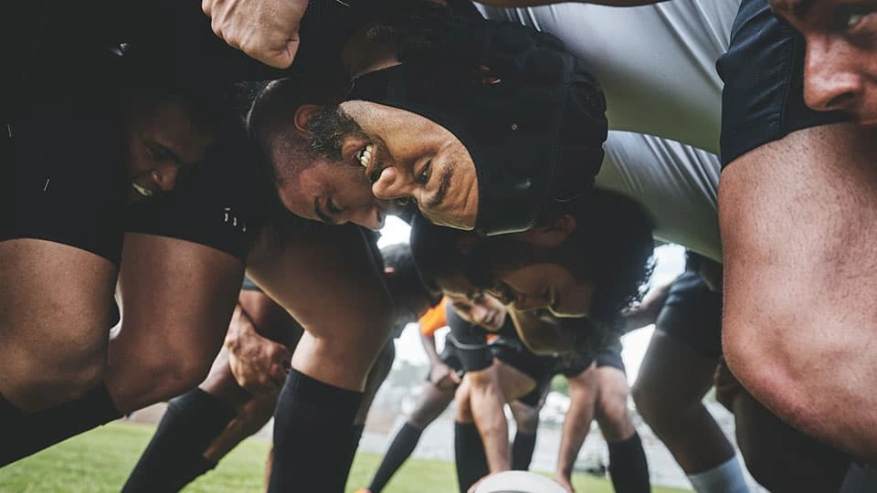 A group of rugby players with their heads together in a match