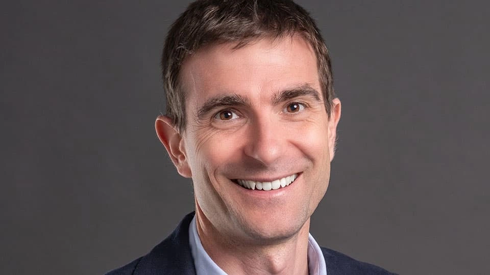 A man smiling into the camera against a plain background