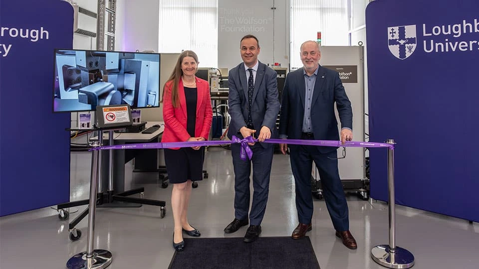 Three people smiling into the camera and cutting a ribbon to open the centre