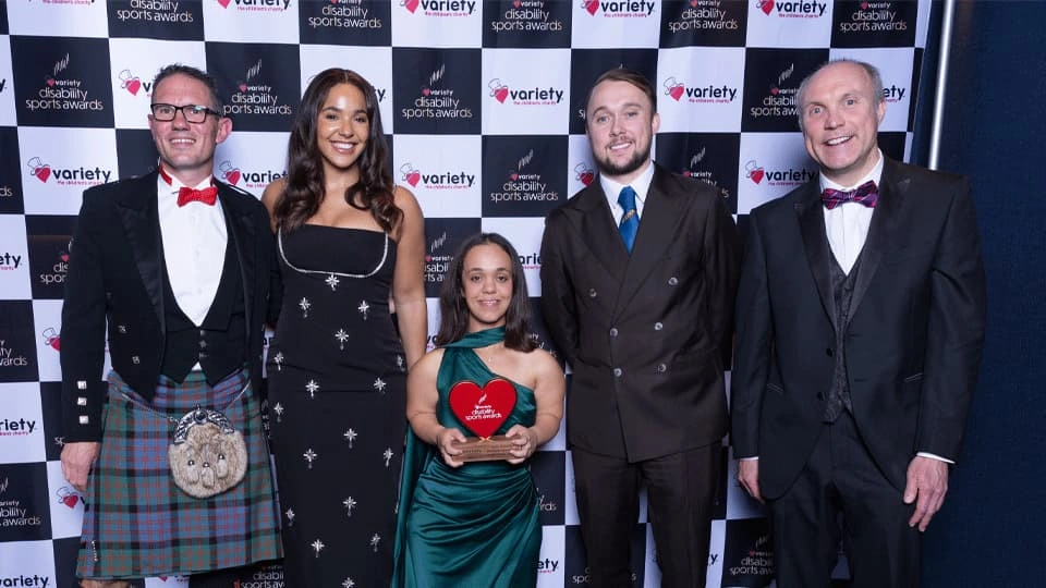 The Variety Awards recipients standing in front of an black and white chequered events background.