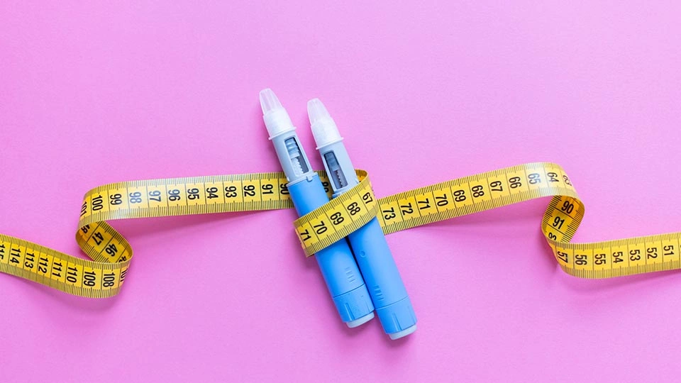 Two weight loss injections wrapped in a tape measure