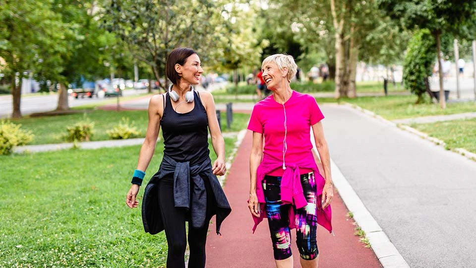 Two women enjoy walking outdoors wearing exercise clothing