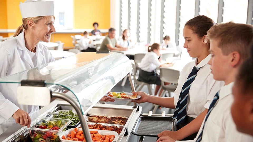 Students queue up for lunch in a school canteen