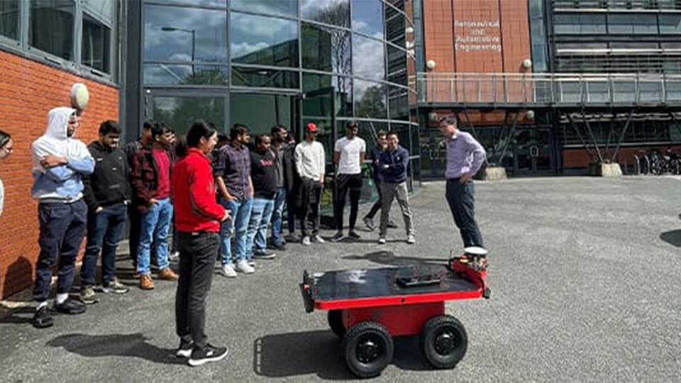 Students gathering round new robot outside penrose atrium