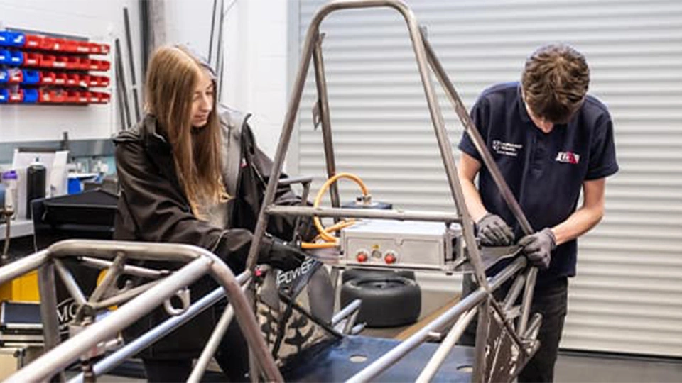 students working on formula car in garage