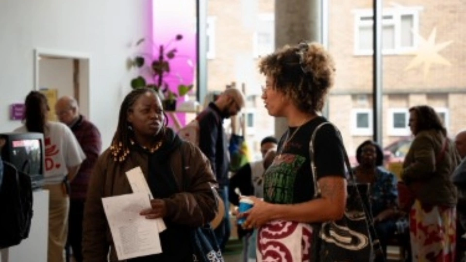 Two people stood chatting inside an arts exhibition