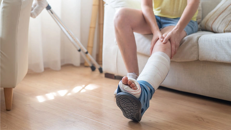 A person sitting on a sofa with their foot in a cast.